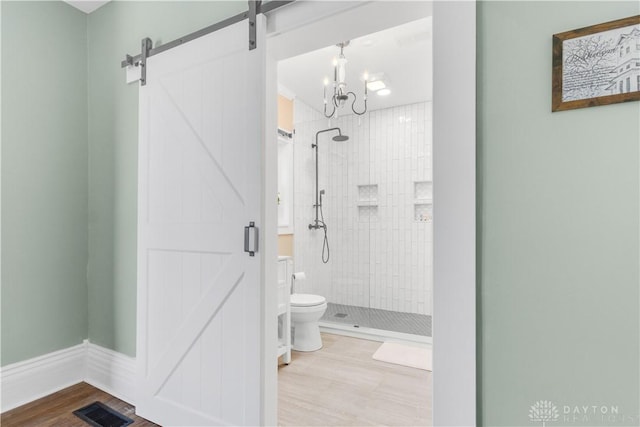 bathroom featuring hardwood / wood-style floors, toilet, tiled shower, and an inviting chandelier