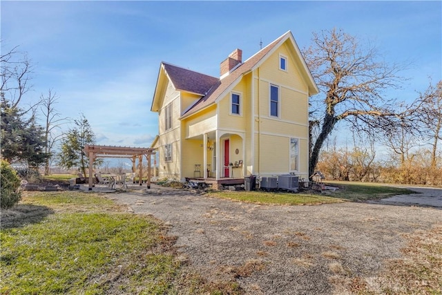 view of front of home with a pergola, central air condition unit, and a front yard