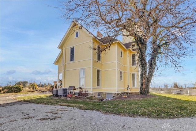 view of side of property with central AC and a lawn