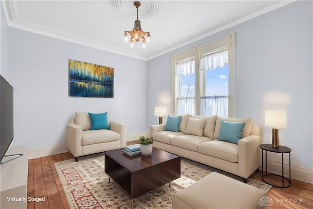 living room with ornamental molding, a notable chandelier, and hardwood / wood-style flooring