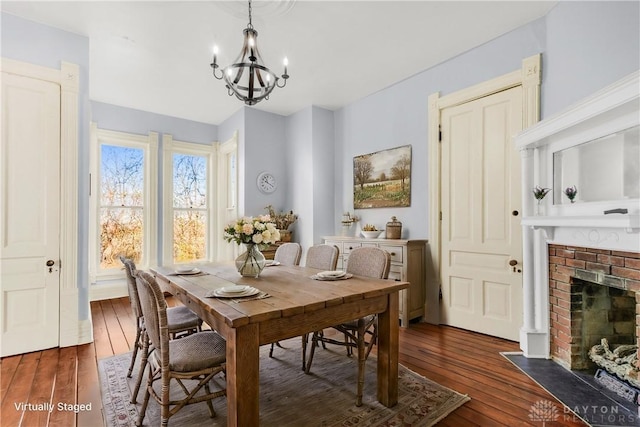 dining area with a fireplace, dark wood-type flooring, and a notable chandelier