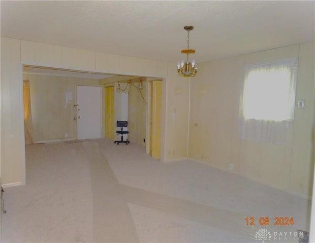 carpeted empty room featuring a notable chandelier