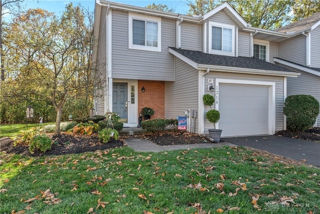 townhome / multi-family property with brick siding, an attached garage, a front yard, and aphalt driveway
