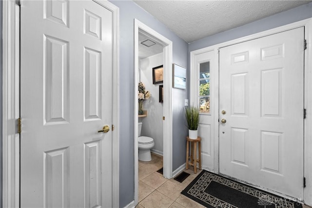 entryway with light tile patterned floors and a textured ceiling