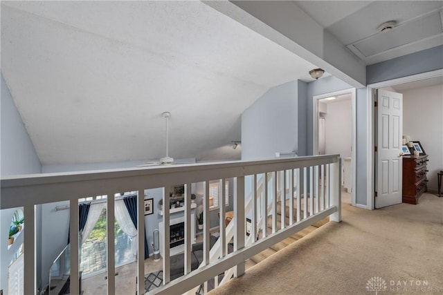 hall with carpet, vaulted ceiling, and an upstairs landing