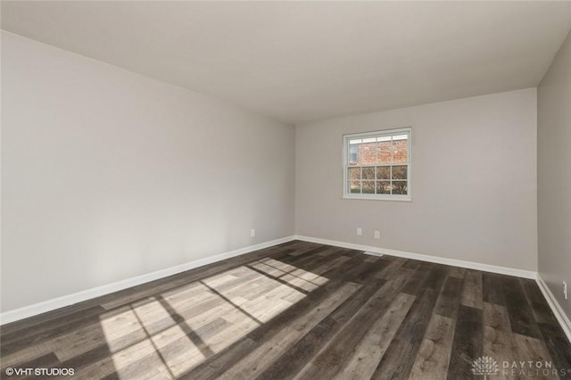 spare room featuring dark wood-style floors and baseboards