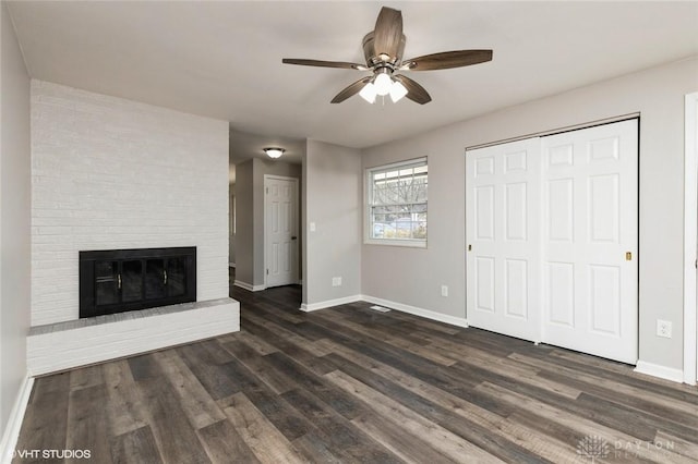 unfurnished living room with dark wood-type flooring, a fireplace, and baseboards