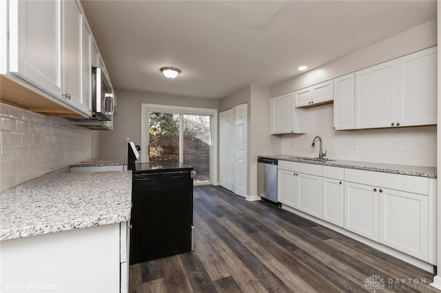 kitchen featuring stainless steel appliances, backsplash, dark wood-type flooring, white cabinets, and a sink