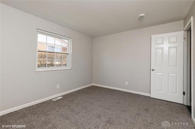 empty room featuring carpet floors, visible vents, and baseboards