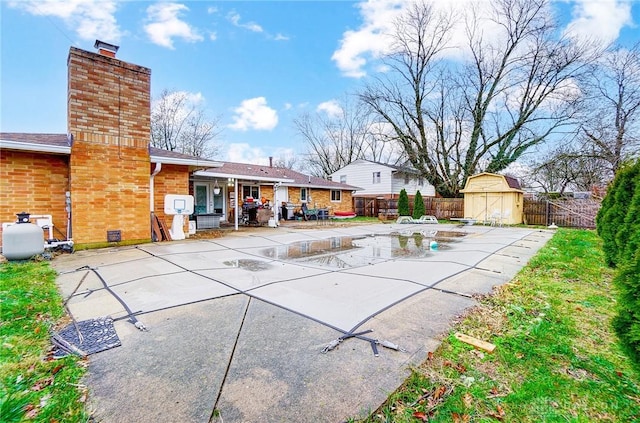 view of patio featuring a covered pool and a storage unit