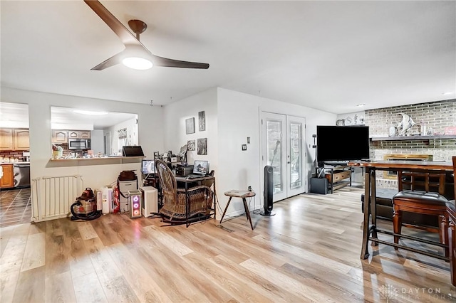 living room featuring ceiling fan, french doors, brick wall, and light hardwood / wood-style flooring