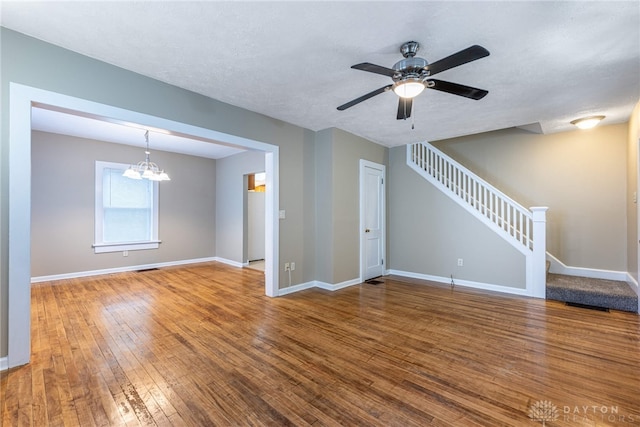 unfurnished living room with wood-type flooring and ceiling fan with notable chandelier