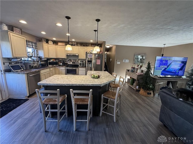 kitchen featuring appliances with stainless steel finishes, a center island, dark wood-type flooring, and a breakfast bar area