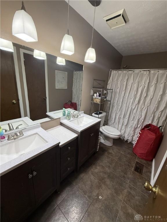 bathroom featuring tile patterned flooring, vanity, toilet, and lofted ceiling