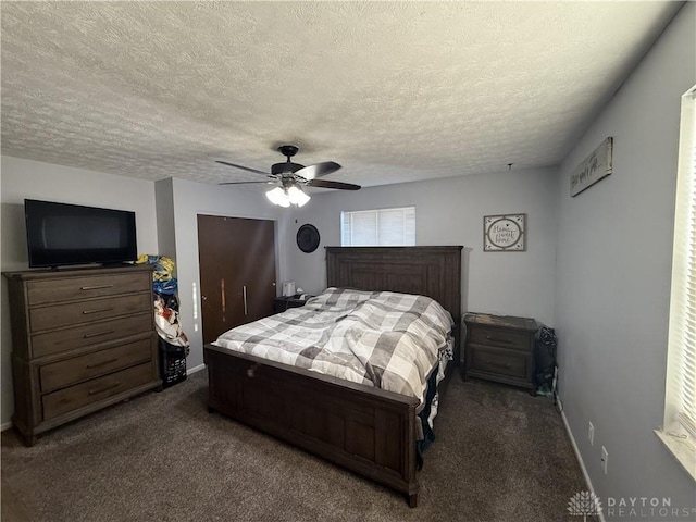 bedroom with ceiling fan, dark carpet, and a textured ceiling