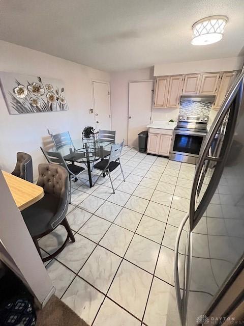 kitchen featuring stainless steel electric stove, decorative backsplash, light brown cabinets, and light tile patterned floors