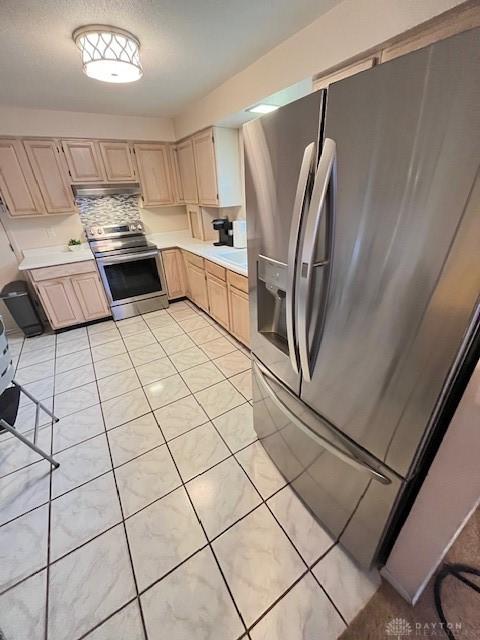 kitchen with light brown cabinets, light tile patterned flooring, appliances with stainless steel finishes, and tasteful backsplash