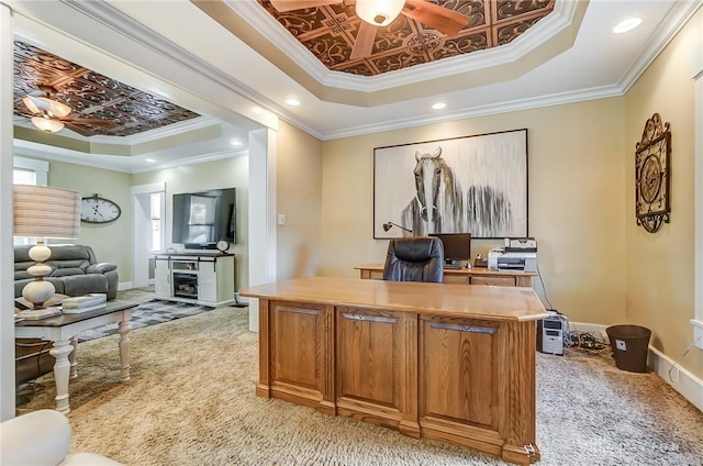 carpeted office space featuring a tray ceiling, ceiling fan, and ornamental molding