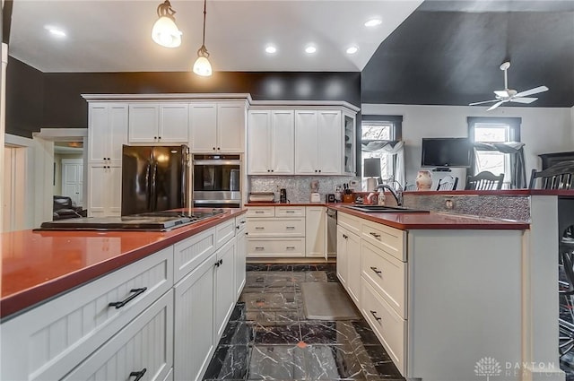 kitchen featuring ceiling fan, sink, hanging light fixtures, backsplash, and black appliances