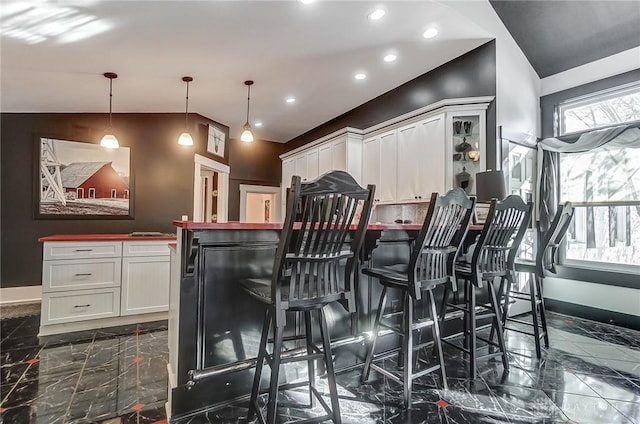 bar featuring decorative backsplash, white cabinetry, lofted ceiling, and hanging light fixtures