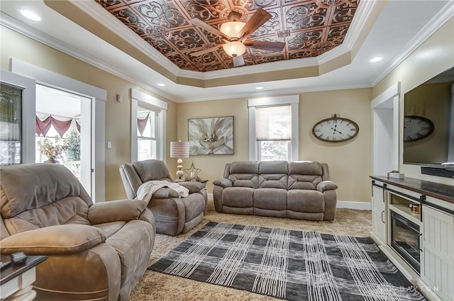 living room with a fireplace, a raised ceiling, ornamental molding, and carpet floors