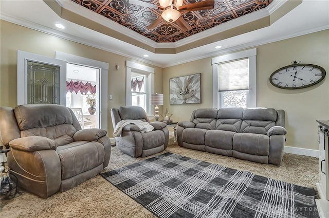 carpeted living room featuring a raised ceiling, ceiling fan, and ornamental molding