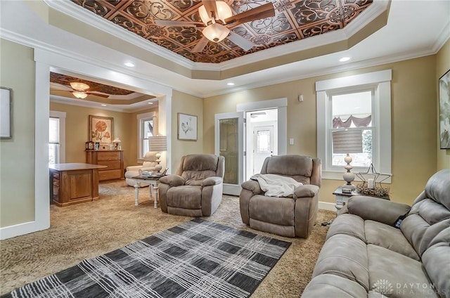 living room with a tray ceiling, ceiling fan, and ornamental molding