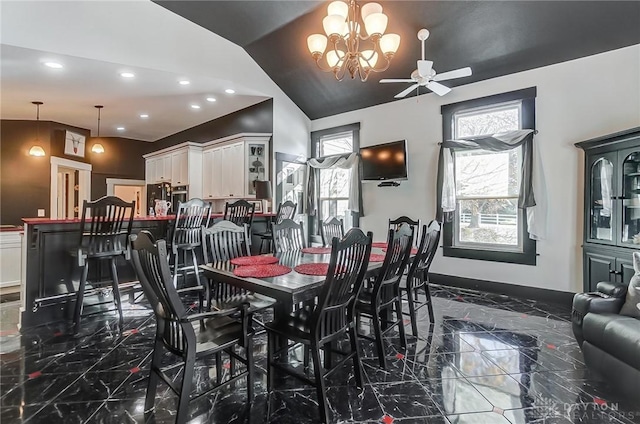 dining space featuring ceiling fan with notable chandelier and vaulted ceiling