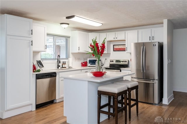 kitchen with white cabinets, a kitchen island, sink, and stainless steel appliances