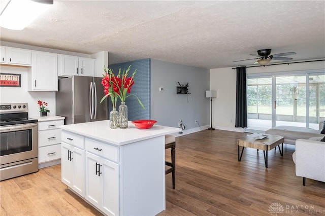 kitchen with white cabinets, appliances with stainless steel finishes, a center island, and light hardwood / wood-style flooring