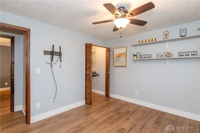 unfurnished room with ceiling fan, light wood-type flooring, and a textured ceiling