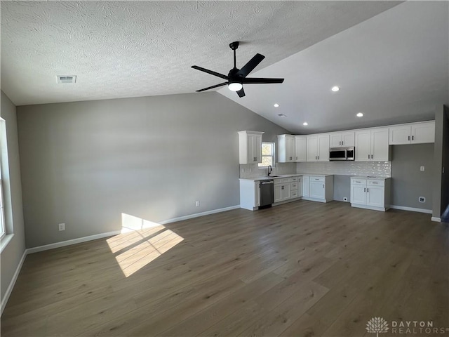 kitchen featuring stainless steel appliances, white cabinetry, dark wood-type flooring, and backsplash