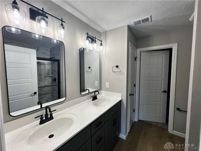 bathroom with vanity, hardwood / wood-style floors, a textured ceiling, and walk in shower