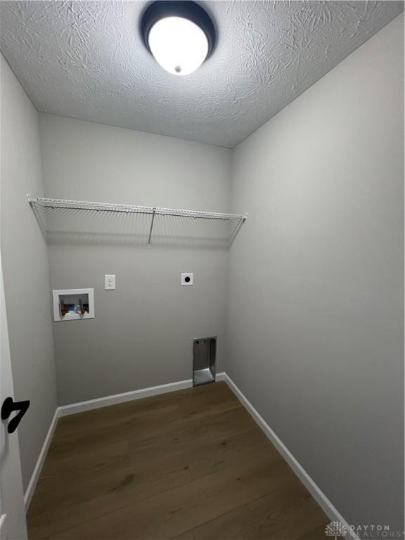 clothes washing area featuring washer hookup, dark wood-type flooring, hookup for an electric dryer, and a textured ceiling