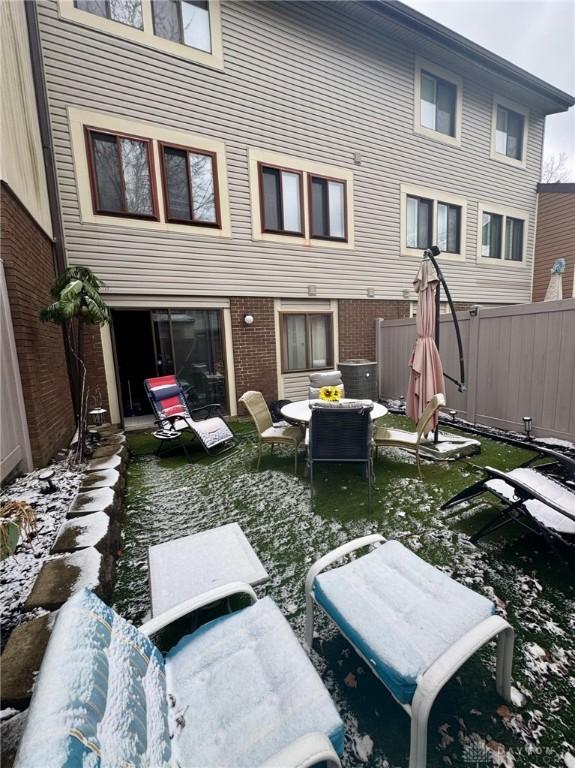 snow covered back of property with a water view and central AC