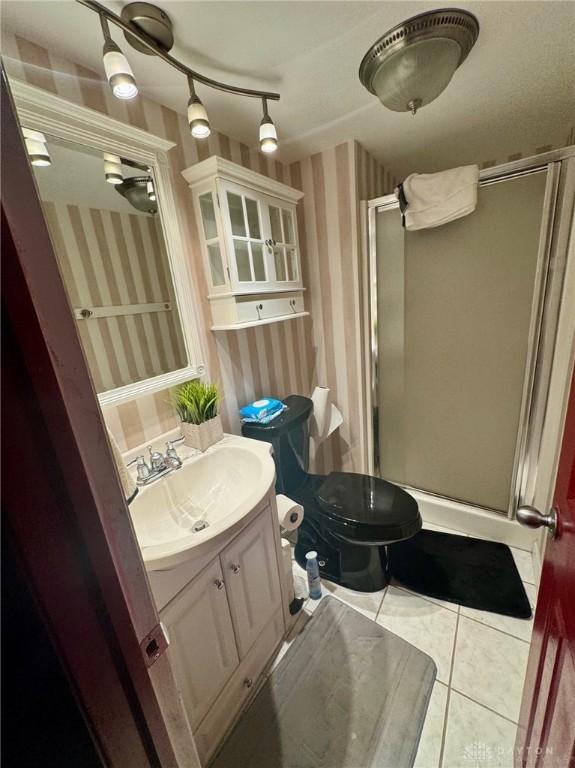 bathroom with toilet, vanity, tile patterned floors, and a shower with shower door