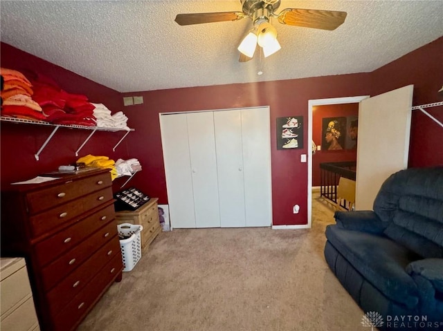 living area with ceiling fan, a textured ceiling, and light carpet