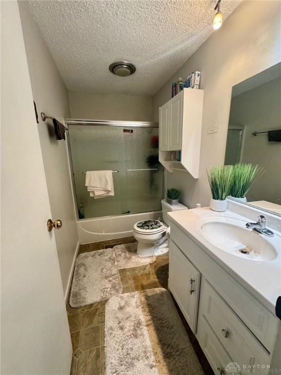 full bathroom featuring vanity, toilet, bath / shower combo with glass door, and a textured ceiling