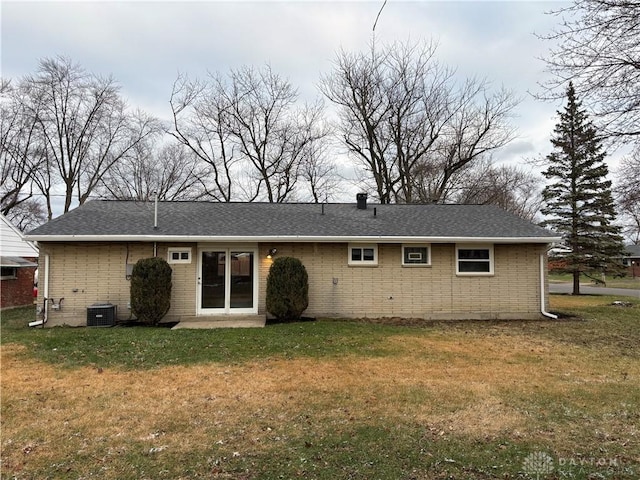 rear view of house featuring central AC unit and a lawn