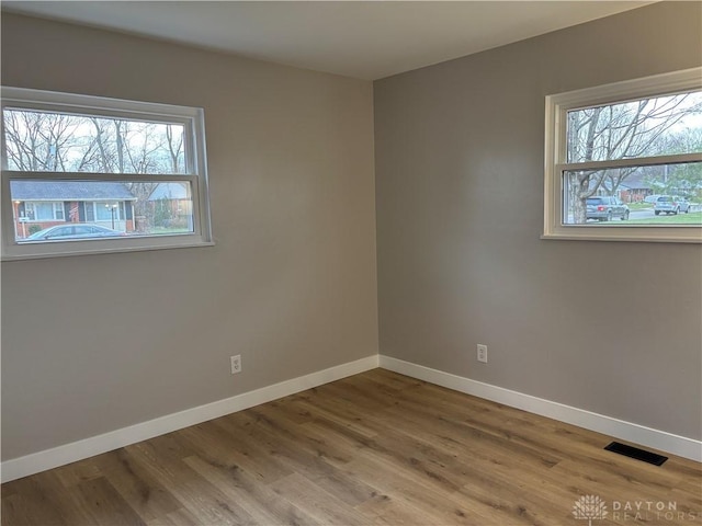 spare room with wood-type flooring and a wealth of natural light