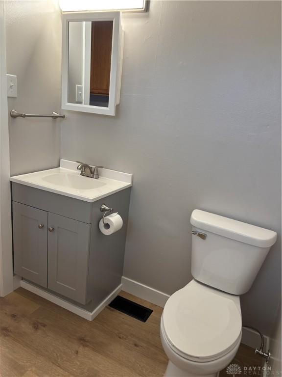 bathroom with toilet, vanity, and hardwood / wood-style flooring