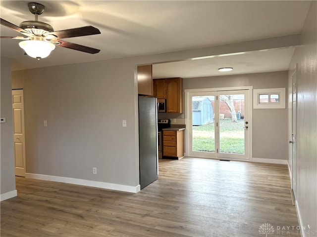 kitchen with appliances with stainless steel finishes, light wood-type flooring, and ceiling fan