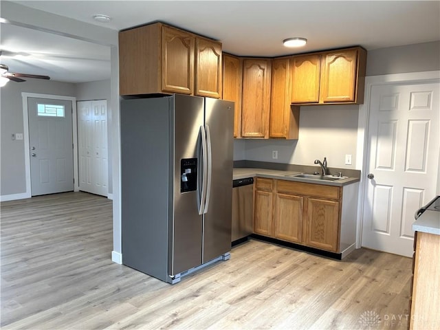 kitchen featuring ceiling fan, sink, stainless steel appliances, and light wood-type flooring