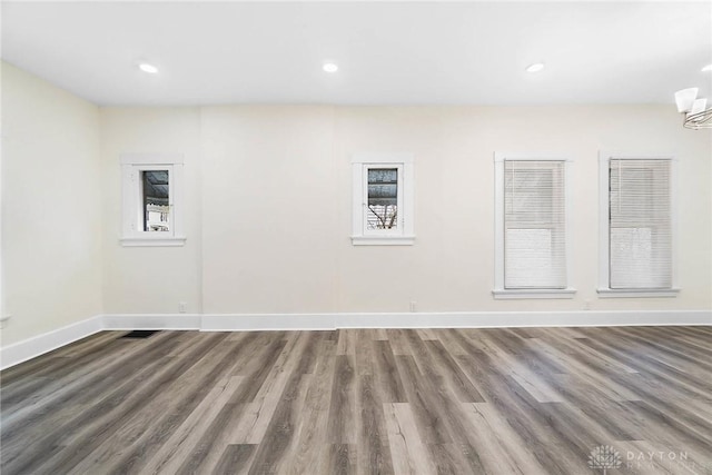 empty room with hardwood / wood-style floors and a notable chandelier