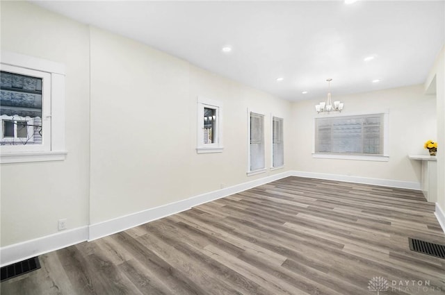 spare room with wood-type flooring and a notable chandelier