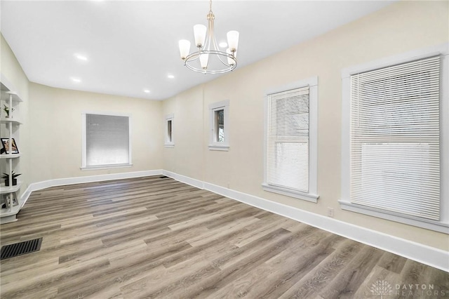 spare room featuring hardwood / wood-style flooring and a notable chandelier