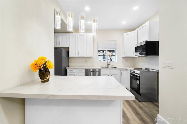 kitchen featuring pendant lighting, sink, light wood-type flooring, appliances with stainless steel finishes, and white cabinetry