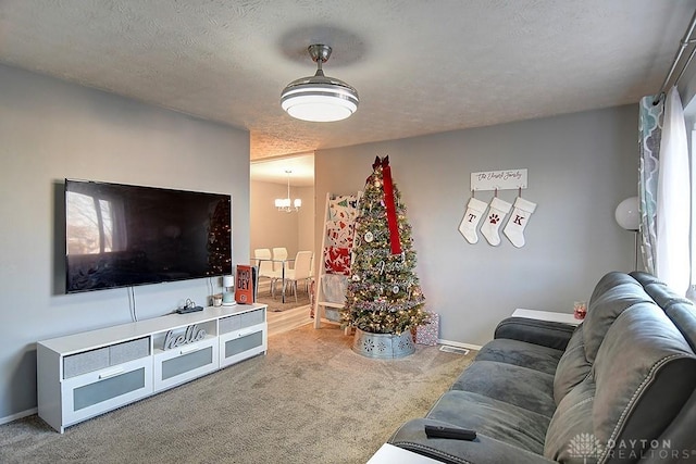 living room with carpet flooring, a textured ceiling, and a chandelier