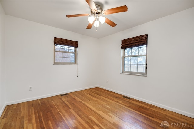 unfurnished room featuring a healthy amount of sunlight, hardwood / wood-style floors, and ceiling fan