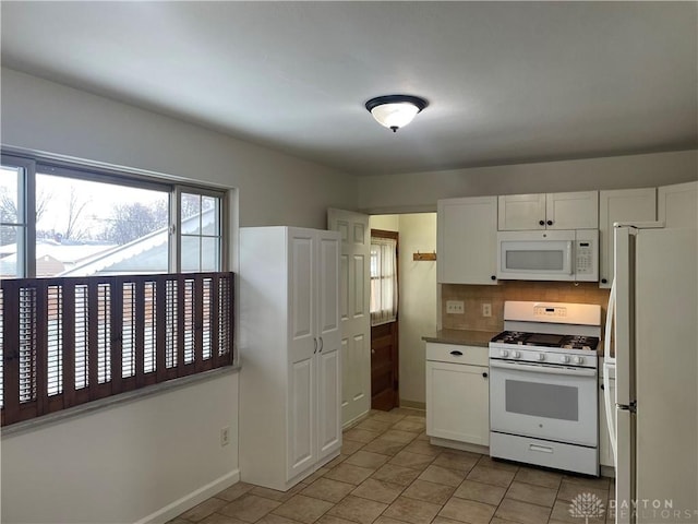 kitchen with light tile patterned floors, white cabinets, white appliances, and decorative backsplash